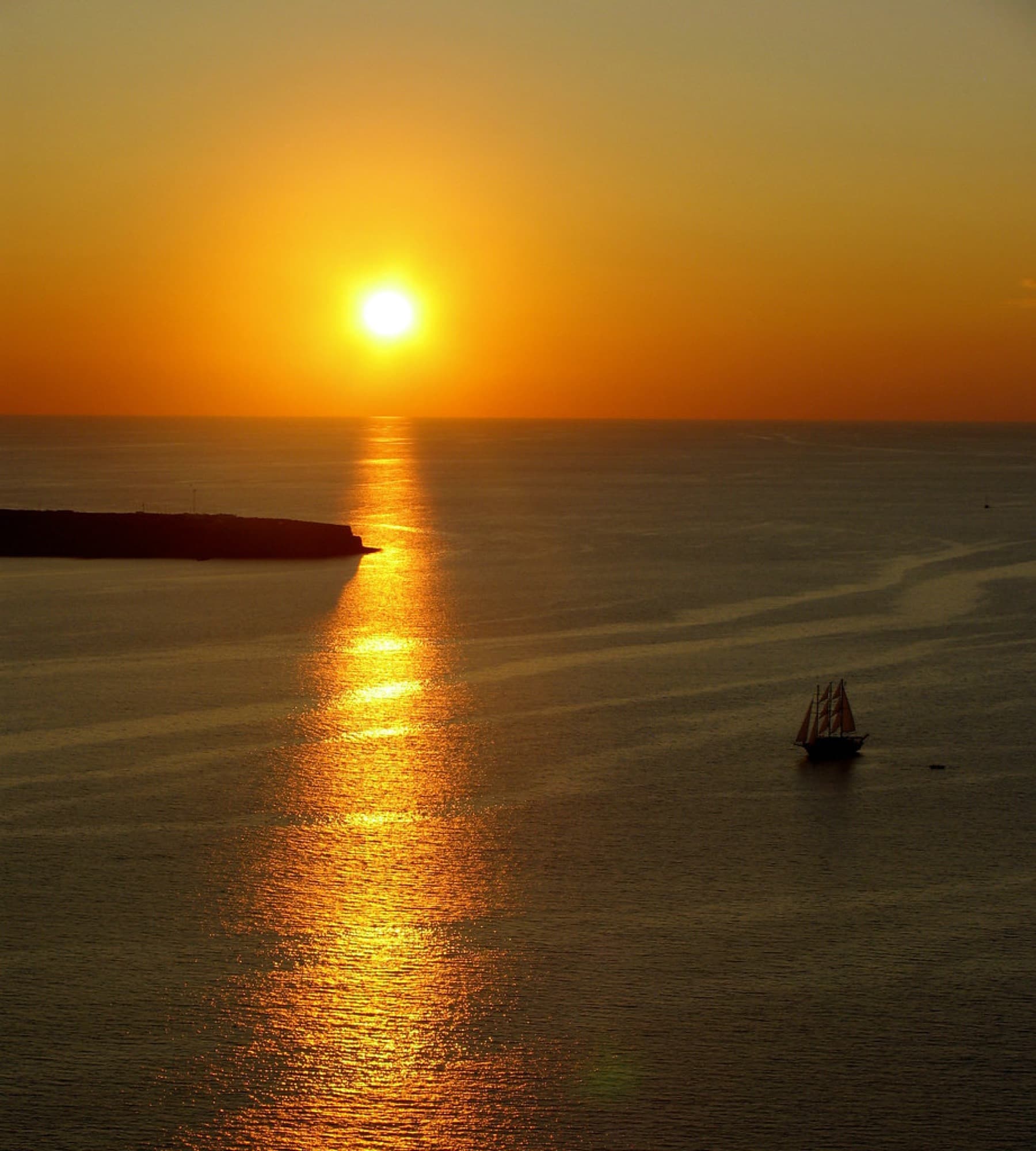 Oia's white terraces above the caldera at golden hour